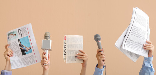 Female hands with microphones and newspapers on color background