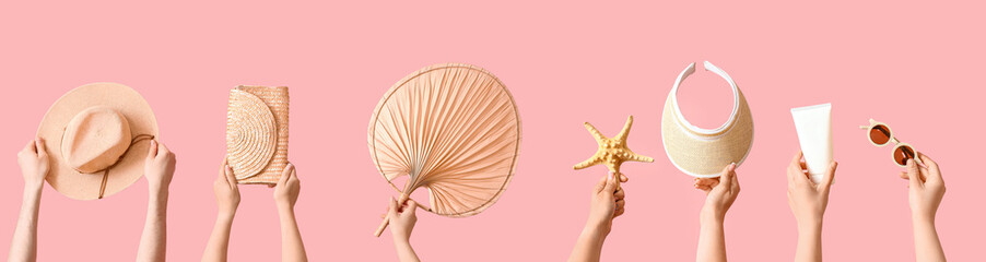 Many hands holding beach accessories on pink background