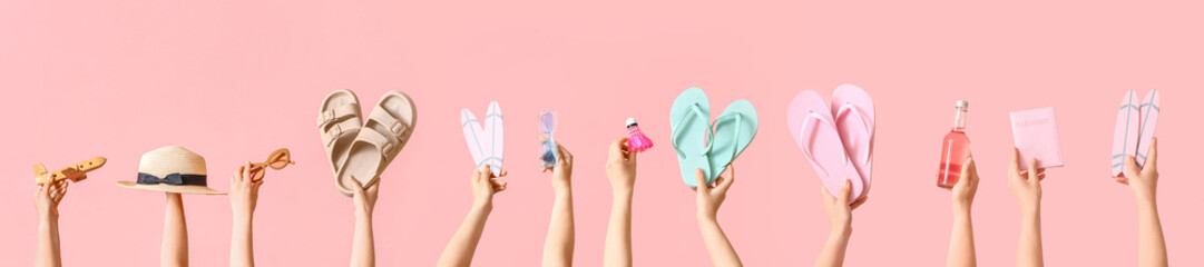 Many hands holding travel accessories on pink background