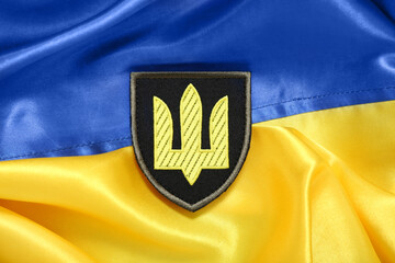Military badge with trident on flag of Ukraine, closeup