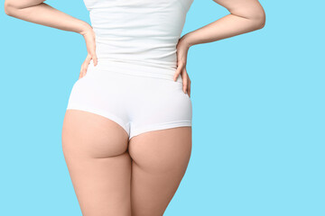 Body positive woman in underwear on blue background, back view