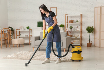 Young woman cleaning floor with vacuum cleaner in living room