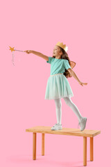 Cute little fairy with wand on bench against pink background