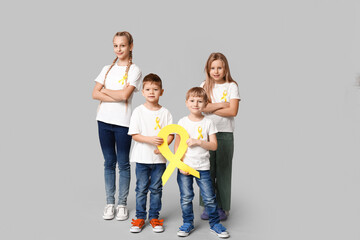 Fototapeta premium Group of kids with yellow ribbons on grey background. International Childhood Cancer Day