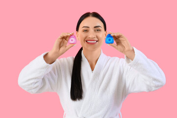 Beautiful young happy woman in bathrobe with different dental floss on pink background