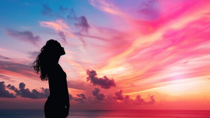 Silhouette of woman with curly hair against vibrant sunset sky