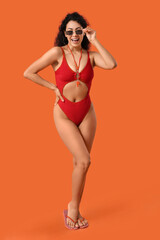 Beautiful young happy African-American female lifeguard on orange background