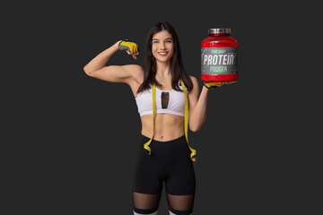 Young sporty woman with bottle of protein powder and measuring tape on dark background