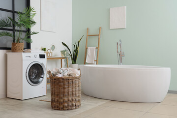 Interior of room with washing machine, laundry basket and bathtub