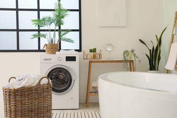 Interior of room with washing machine, laundry basket and bathtub