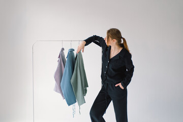 A collection of Colorful clothes in varying shades from light pink to dark blue is displayed on a metal clothing rack.