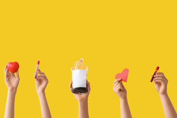 Female hands holding blood pack, test tubes and hearts on yellow background. Blood donation concept