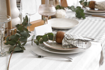 Beautiful table setting with eucalyptus branches for wedding celebration in room, closeup