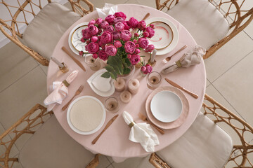 Beautiful table setting with pink roses and candles for wedding celebration in room, top view