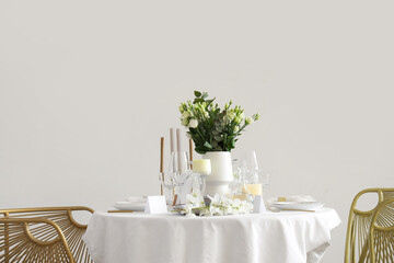 Beautiful table setting with white flowers and candles for wedding celebration in room