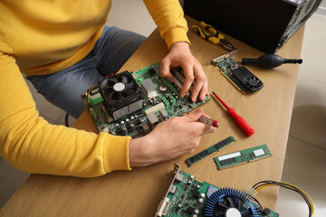Young technician with screwdriver repairing computer at table in service center, closeup