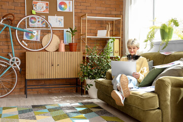 Female graphic designer working with laptop on sofa in office