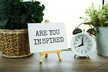 Are you inspired text message on paper card with wooden easel on wooden table background,...