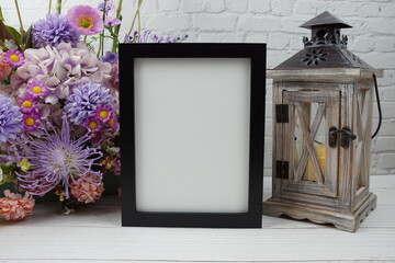 Empty Photo frame mock up with flower bouquet and home decorations on wooden background