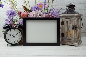 Empty Photo frame mock up with flower bouquet and home decorations on wooden background