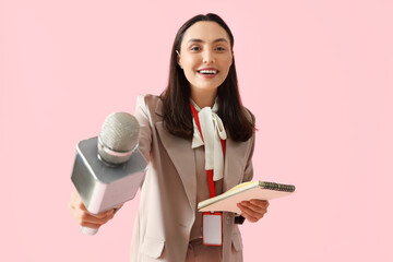 Female reporter with microphone and notebook on pink background