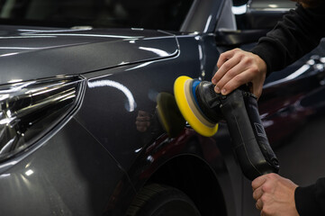A master polishes the surface of a car body. 