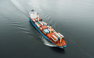 Fototapeta premium Aerial view of cargo ship in the ocean carrying containers