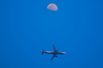 Airplane flying under the moon