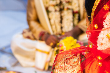 Hindu traditional marriage rites being performed with bride and groom sitting together in presence of priest. Bride in red saree. Symbolic photo of hindu religious culture  of wedding ceremony.