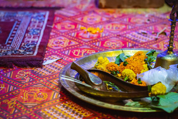 Religious items for hindu puja rituals kept on copper plate for performing the rites. Marigold flowers and copper utensils are symbolic to traditional hindu culture.