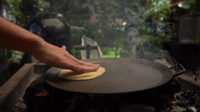 woman's hand cooking hand-made corn tortilla on the comal