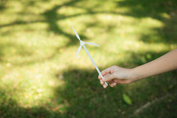 Little boy holding windmill or wind turbine mockup model to promote eco clean and renewable energy...