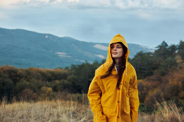 A woman exploring the stunning beauty of nature in a yellow raincoat under the majestic mountains