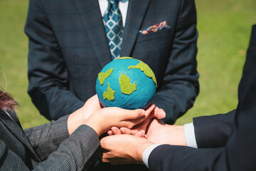 Group of business people hold planet Earth globe together as Earth day concept. Mission to save...