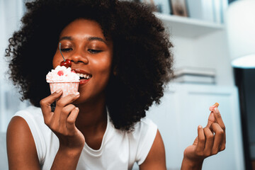 Portrait of beautiful young African blogger tasting piece of cherry cake in concept special...