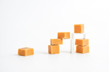 Obraz premium Caramel candies stacked on white surface