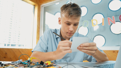 Smart happy boy inspect or learning to use electronic tool while taking a note. Happy highschool...