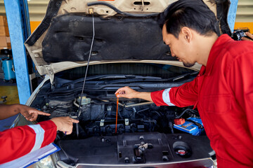 Asian technician team working for checking engine oil in engine room of car.