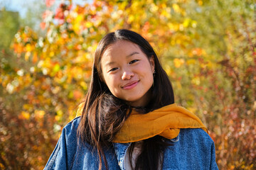 Young Asian woman smiling and looking at camera in a park in autumn.