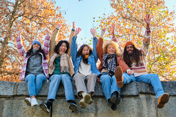 Happy diverse friends celebrating success and having fun all together. Group of cheerful ecstatic people rising their arms and shout Yes we did it, Hooray.