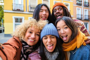 Multiracial group of friends having fun and taking a selfie together outdoors on city street. Young...