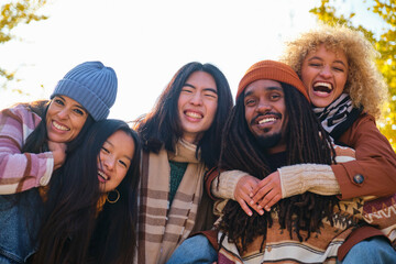 Diverse group of young friends having fun together outdoors in autumn. Student people laughing...