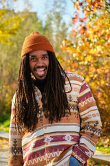 African American young man with dreadlocks laughing and looking at camera in a sunny day of autumn.