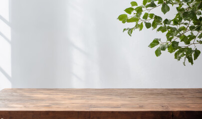 Product presentation. Empty Table, White Wall, Green Plant Leaves, Natural Light Shadows, Rustic Wood Surface, Bright Interior Room, Fresh Foliage, Sunlight Pattern on Wall