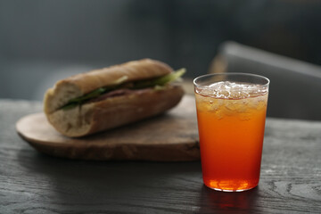 orange lemonade with baguette sandwich on background on black wood table