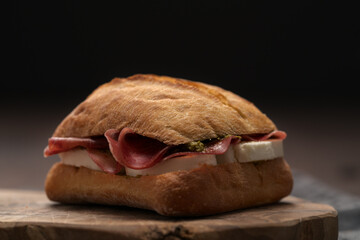Sandwich with bresaola, mozzarella and pest on olive board