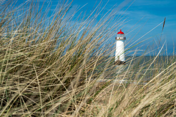 The sand dunes, and the grade II listed building Point of Ayr Lighthouse at Talacre beach in Wales on a sunny summer day.