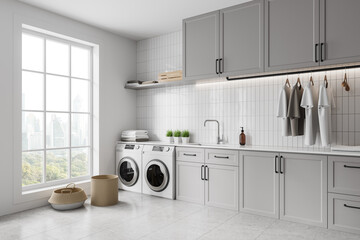 Grey home laundry interior with washing cabinet and clothes, panoramic window