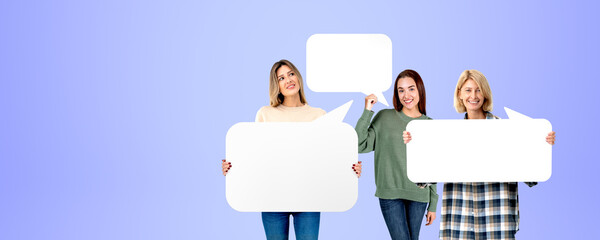 Three smiling women holding mockup speech bubbles on empty background