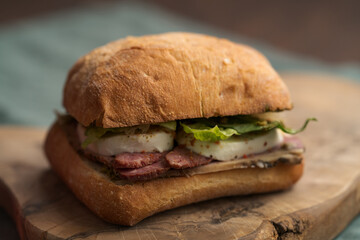 Roast beef and mozzarella sandwich with ciabatta bun on olive board